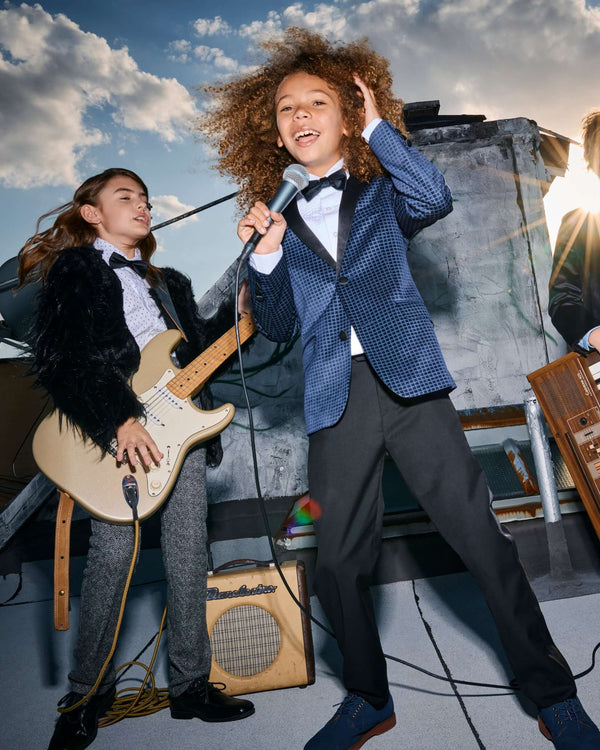 Child wearing a Navy Geo Velvet Tuxedo Jacket while singing on a rooftop, showcasing a fun and stylish look.