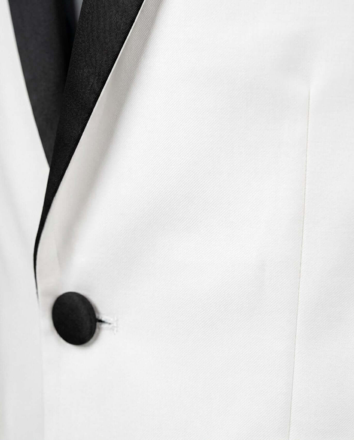 Close-up of White Tuxedo Suit Jacket featuring satin lapels and button-front closure.