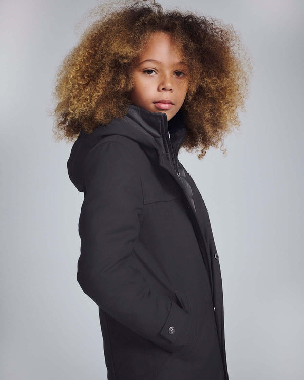 Black Urban Gotham Coat on a young model showcasing style and warmth with its sleek design.