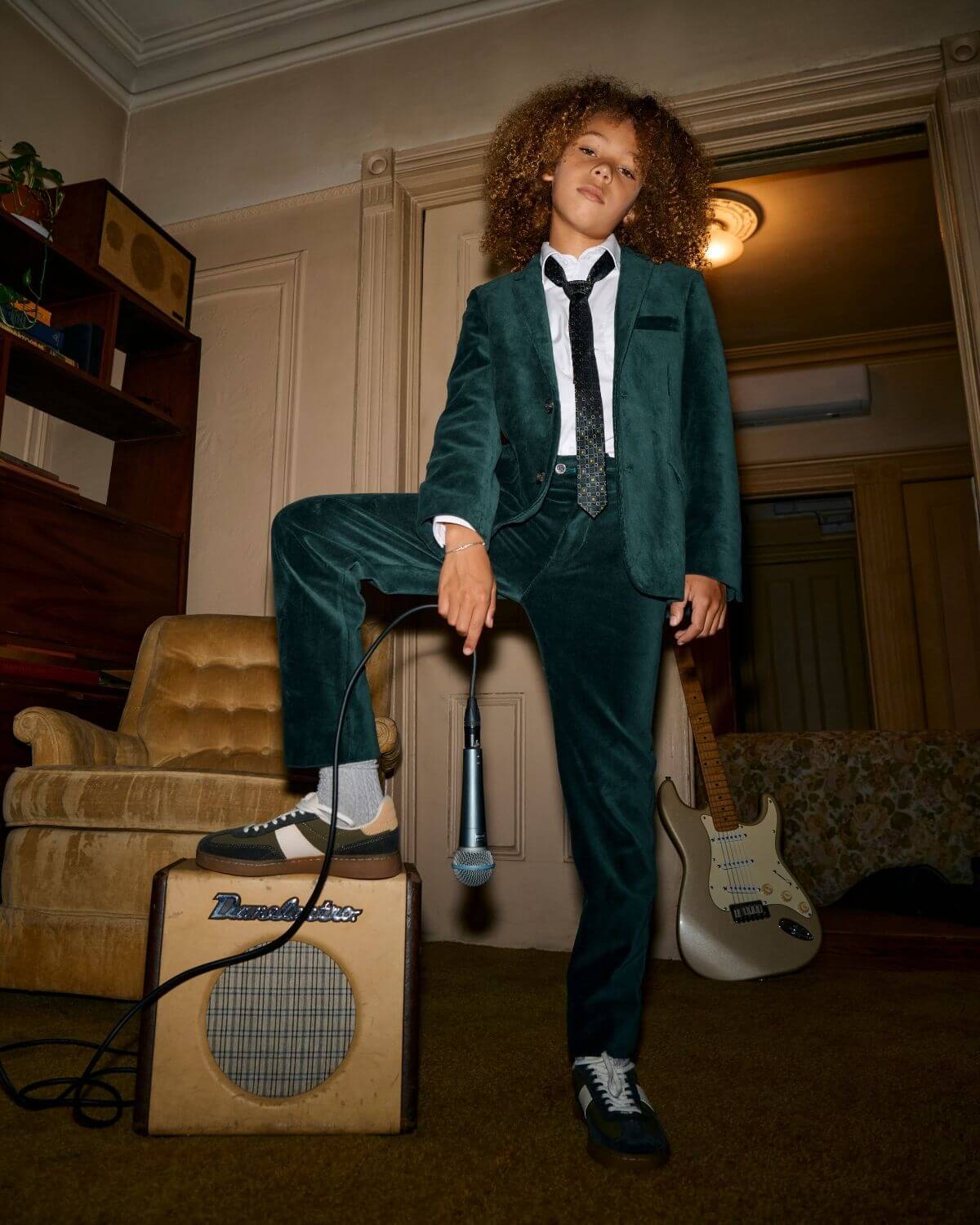 Child wearing Evergreen Velvet Blazer with stylish accessories, posing confidently in a retro setting.