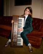 Child wearing Evergreen Velvet Suit Pants while playing a vintage keyboard.