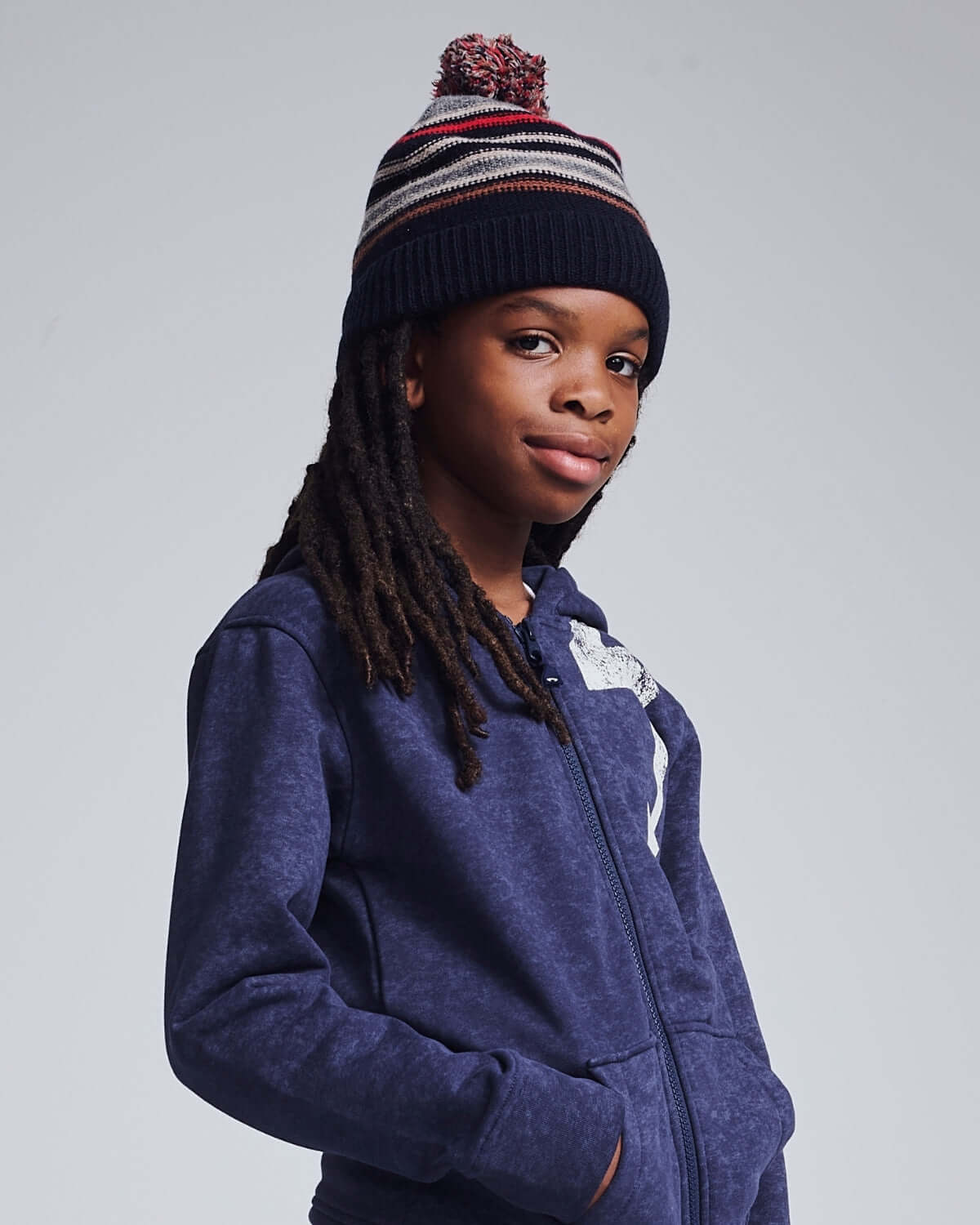 Child wearing a Navy Blue Wind Hat with pom pom, styled in a cozy navy hoodie.