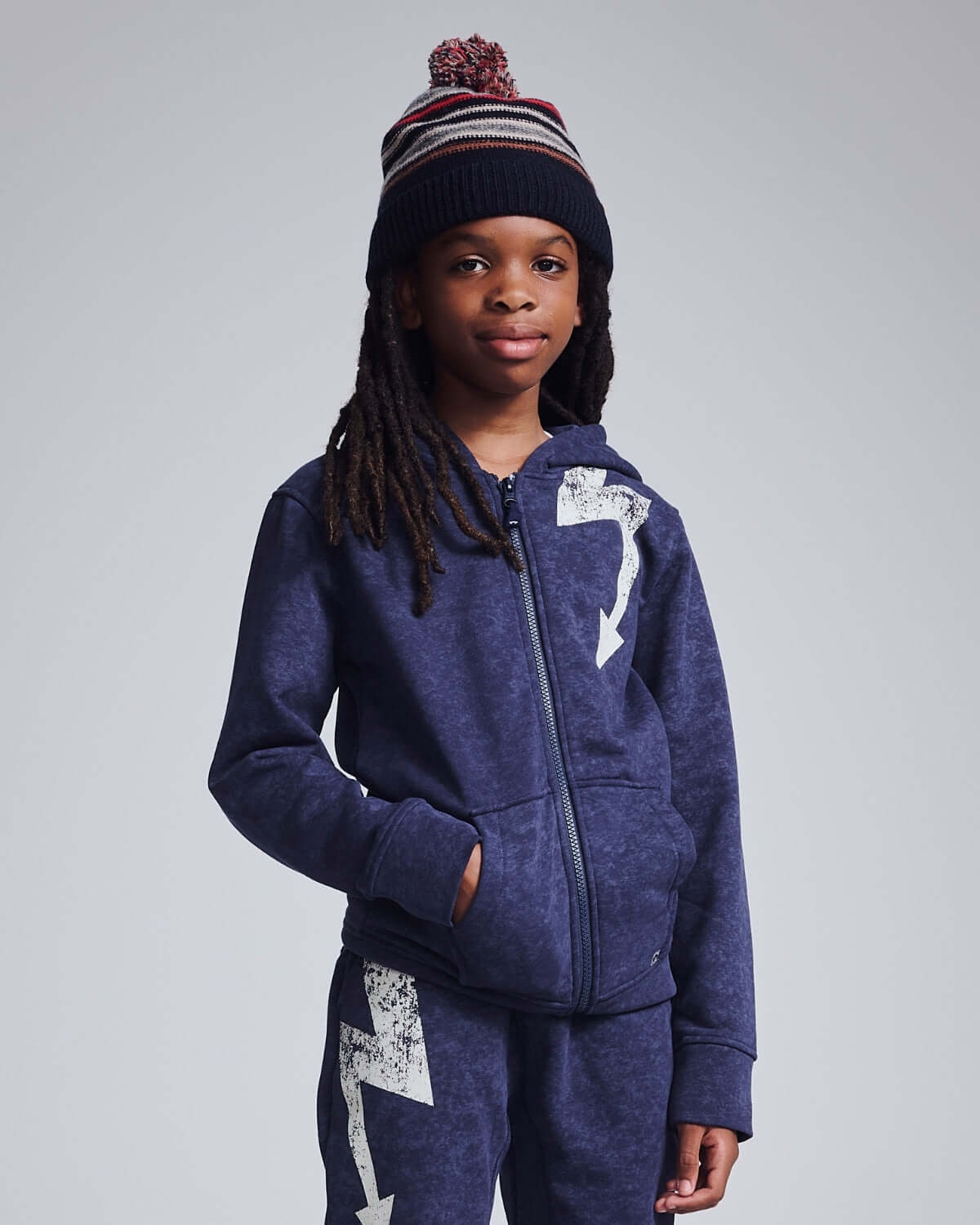 Kid wearing Navy Blue Wind Hat with pom pom, styled in a cozy outfit, perfect for outdoor adventures.