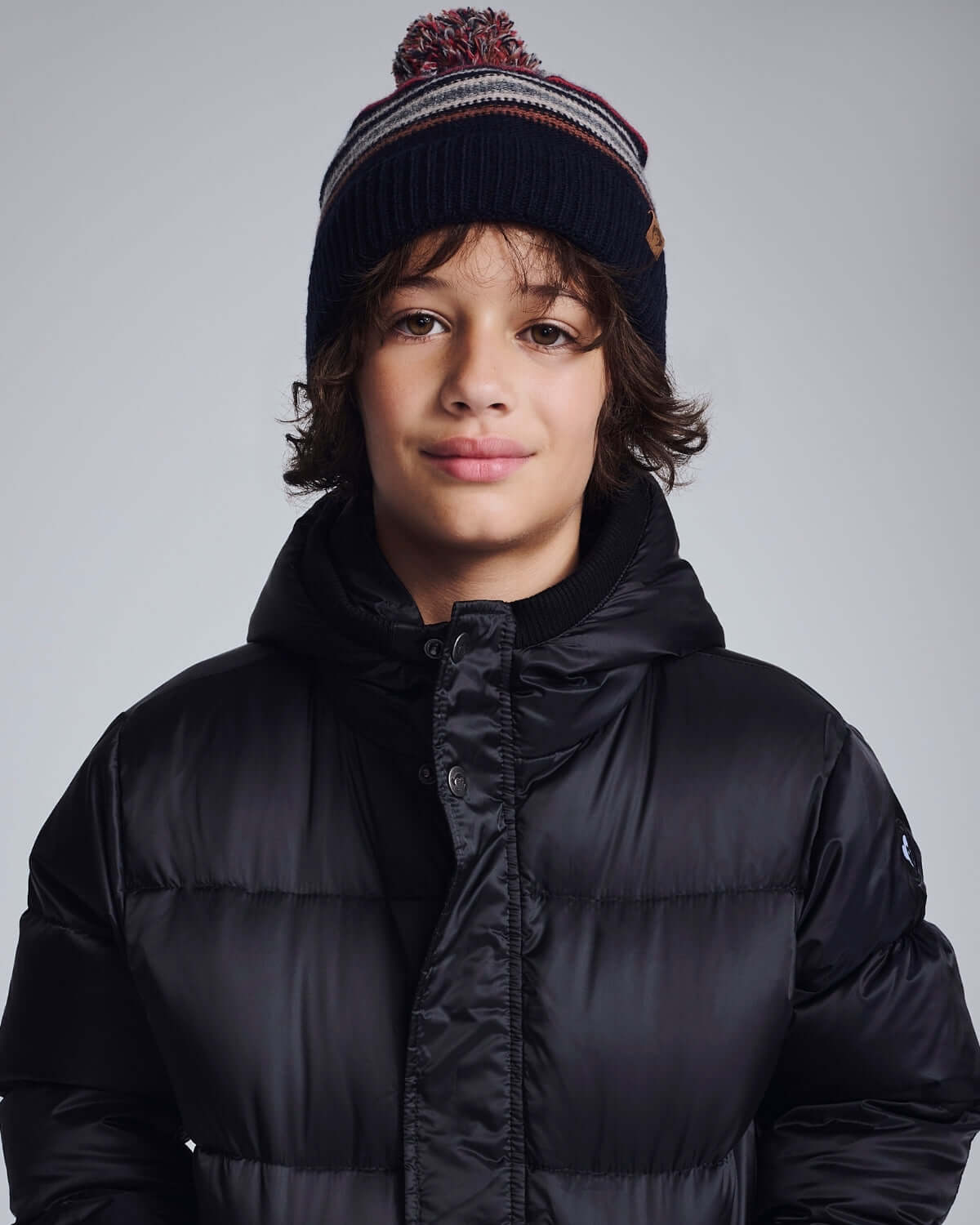 Boy wearing a Navy Blue Wind Hat with a pom pom, styled for outdoor adventures in winter clothing.