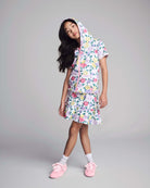 Young girl wearing a floral outfit with pink shoes on a gray background