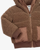 A close-up of a brown sherpa fleece zip-up jacket with quilted brown puffer panels on the front and ribbed brown cuffs and hem.