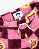 Close-up of a pink and dark brown checkered plush fleece garment with yellow smiley face details and a white drawstring, showing the APPAMAN neck label.