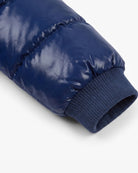 Close-up of a navy blue puffer jacket sleeve with a ribbed knit cuff, shown on a clean white background.