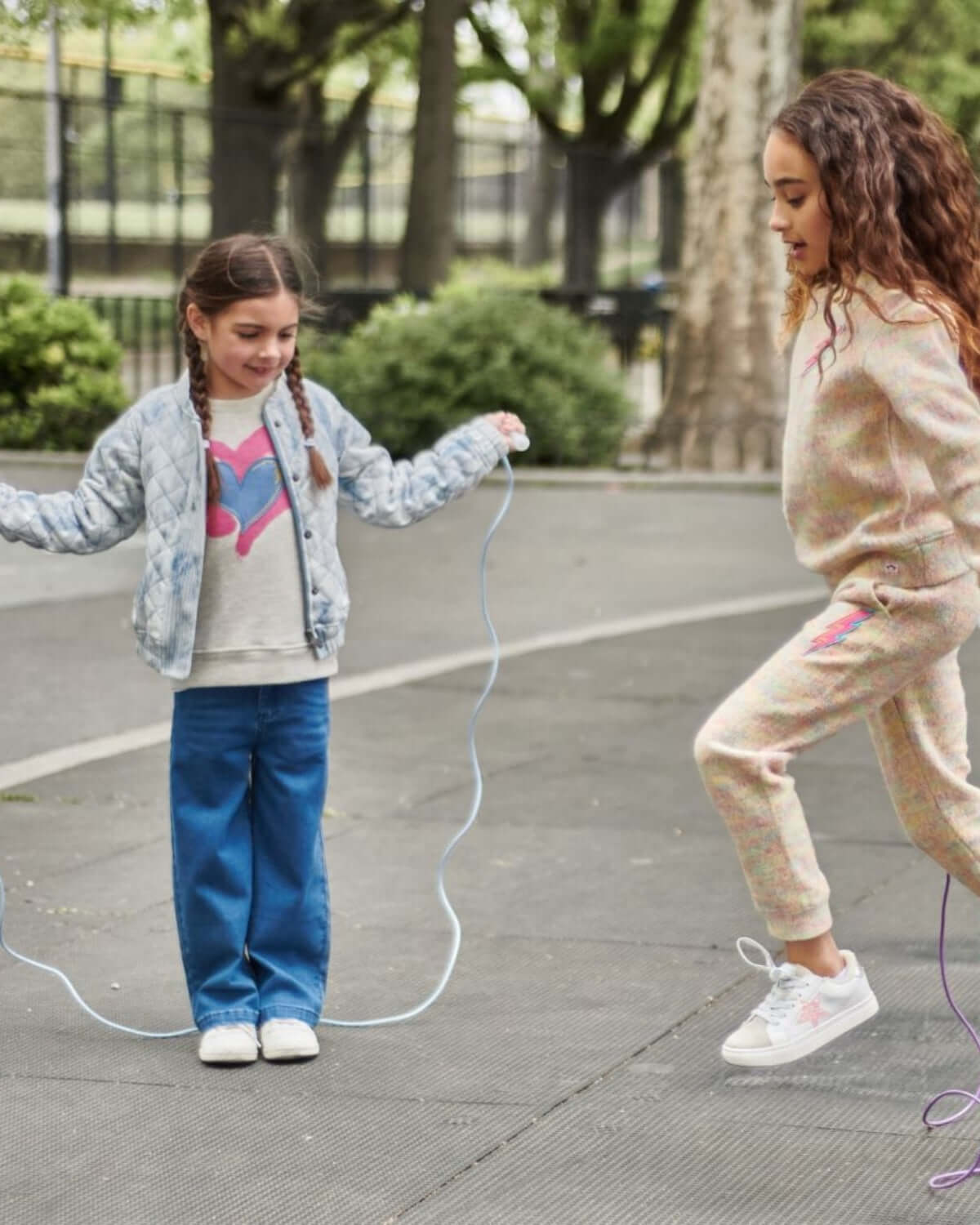 Two girls playing jump rope outdoors, one wearing Medium Wash Liana Pant, showcasing fun and style in casual attire.