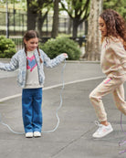 Two girls playing jump rope outdoors, one wearing Medium Wash Liana Pant, showcasing fun and style in casual attire.