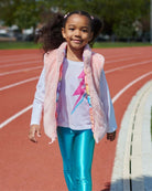 Girl wearing Lightning Bolt Adler Tee with bright leggings on a running track, radiating joy and style.
