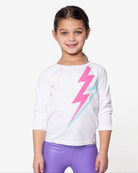 Lightning Bolt Adler Tee featuring a girl wearing a white top with a colorful lightning bolt design.