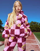 Pink Melanie Sherpa Jacket worn by a girl, featuring plush sherpa material and playful checkered pattern.