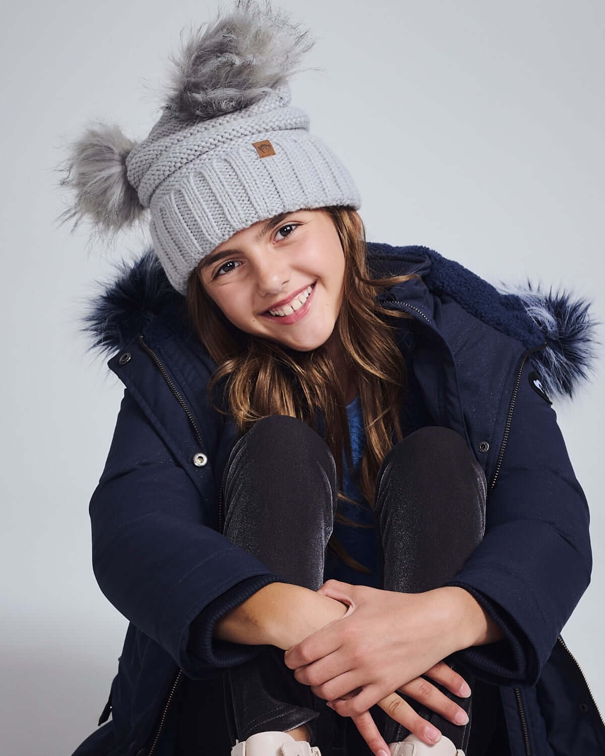 Shiny Silver Mia Faux Fur Pom Beanie on a smiling girl, perfect for winter fun and warmth.