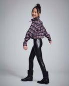 Girl wearing Pink Plaid Polly Cropped Flannel shirt with black leather leggings and boots, smiling playfully.