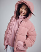 Pink Teddy Puffer Coat worn by a smiling girl, showcasing its plush sherpa material and cozy hood.