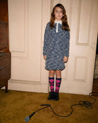 Girl wearing a Navy Tweed Polo Dress with a classic collar and sparkly buttons, styled with fun socks.