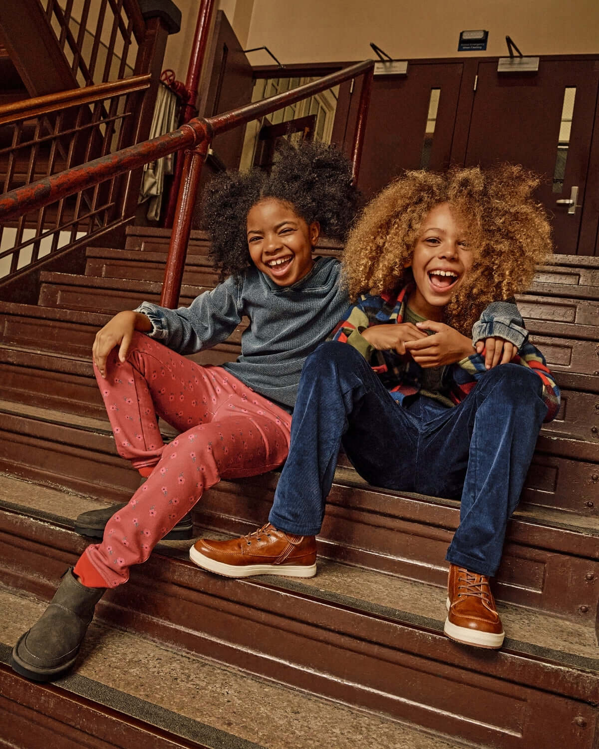 Kids enjoying their time sitting on stairs wearing Dusk Blue Pullover Hoodie and colorful pants, showcasing casual style.