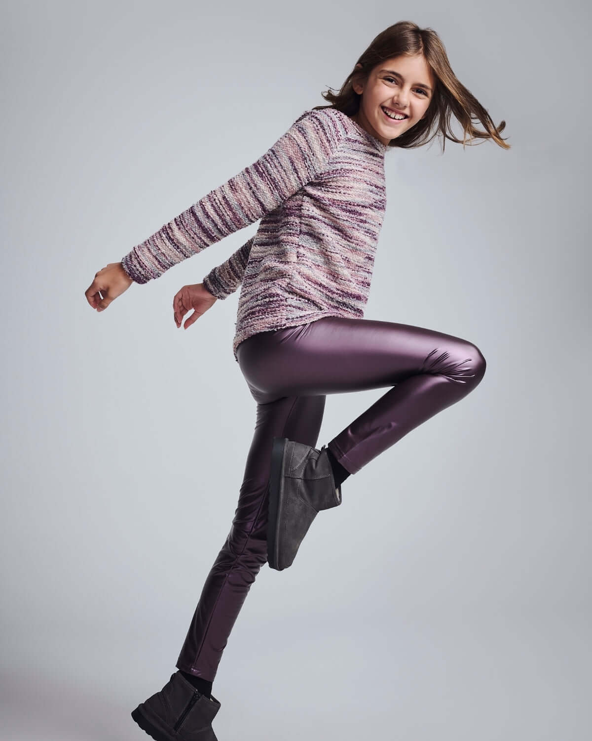 Girl smiling and jumping in Purple Shine Leggings, showcasing vibrant color and comfortable fit.