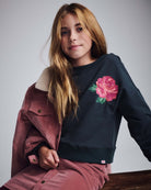 Rose Lisa Cropped Sweatshirt worn by a girl, featuring a pink rose embroidery and styled with a pink jacket.
