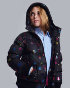 Girl wearing Rainbow Snowflakes Slim Puffy Coat with colorful snowflake designs against gray background.