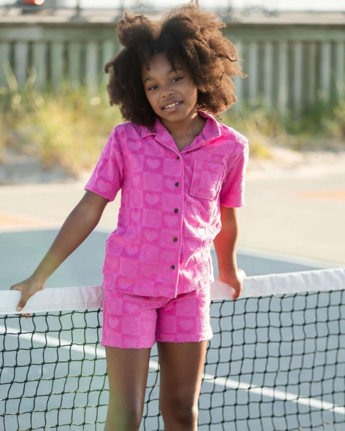 Girl wearing Sunny Check Resort Terry Shorts with heart patterns and matching shirt, perfect for sunny days.