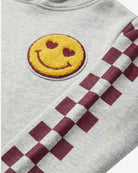 Close-up of the Oatmeal Tunic Hoodie featuring a heart-eyes smiley patch and checkered pattern on the arm.