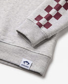 Close-up of Appaman's Oatmeal Tunic Hoodie sleeve with checker design and logo detailing.