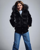 Girl smiling in a stylish black puffer jacket with fur hood, paired with Medium Wash Wide Leg Jeans.