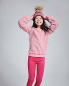 Girl wearing the Ivy Rose Willow Top with a playful expression, styled with pink leggings and a colorful hat.