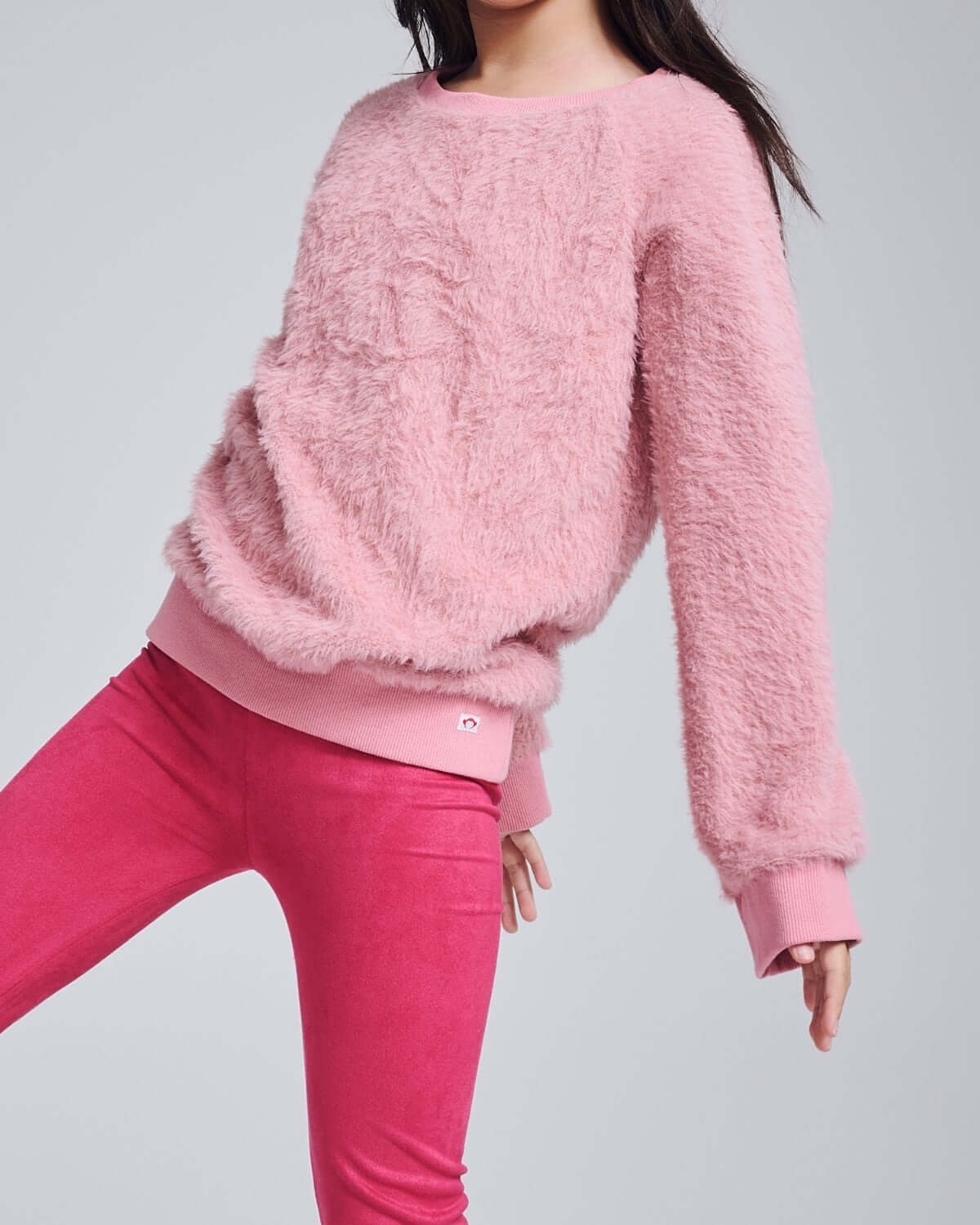 A child wearing the cozy Ivy Rose Willow Top in soft pink, paired with vibrant pink leggings, ideal for stylish play.