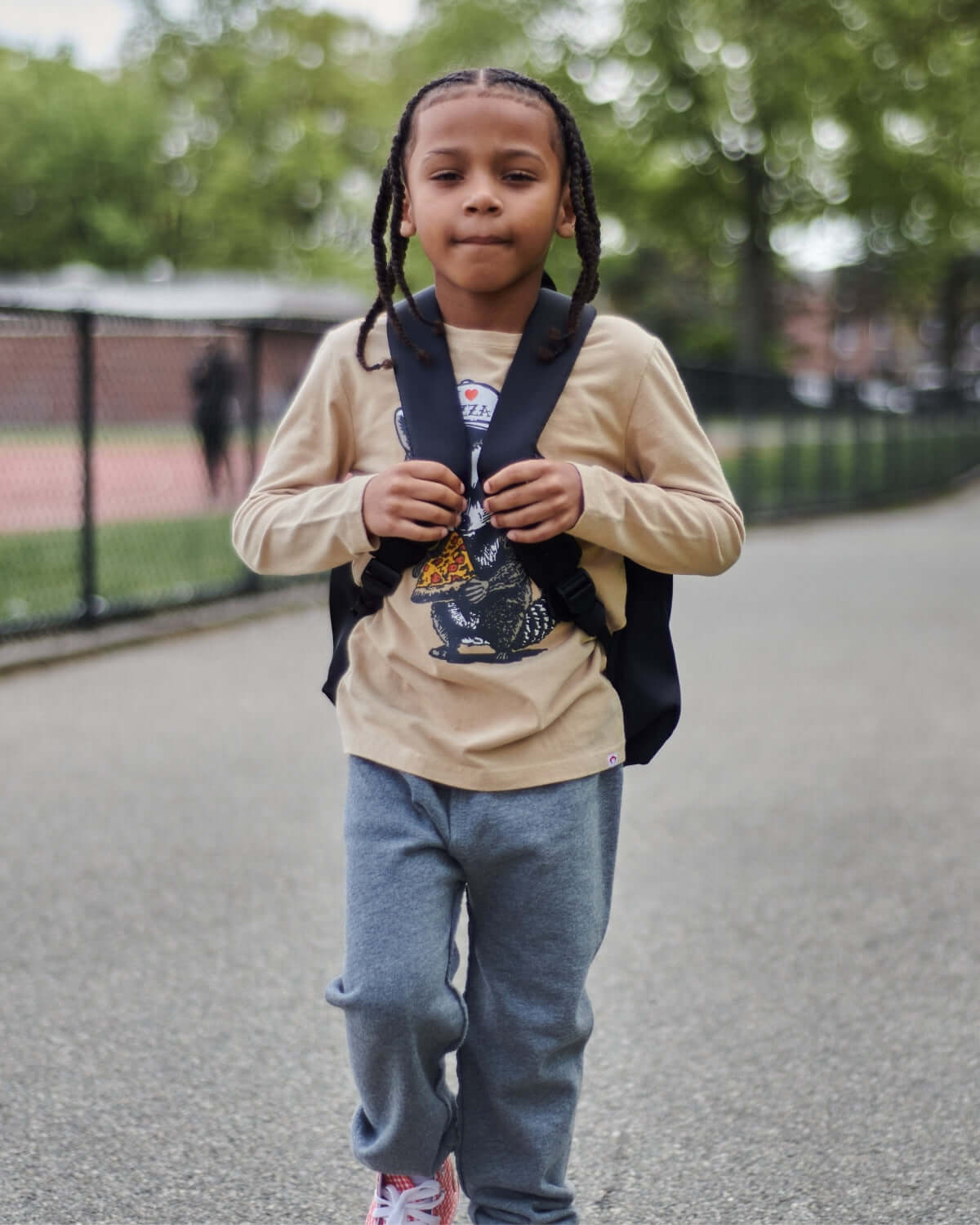 Child wearing Heather Grey Gym Sweatpants, carrying a black backpack while walking outdoors.
