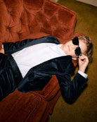 Chic kid in a midnight velvet blazer, lounging on a retro couch, rocking shades—style meets comfort in kids clothes!