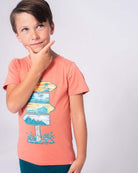 Stylish boy in vibrant Destination Fun Graphic Tee, imagining beach adventures in comfy, high-quality kids clothes.