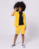 Stylish kid rocking a yellow short set, black tee, and sunglasses, ready for summer fun—perfect boys’ and girls’ clothes!