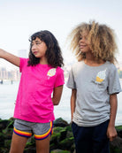 Two kids in playful ice cream tees, enjoying a sunny day by the water—stylish summer vibes for little adventurers!
