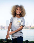 Happy child in a playful gray pocket tee with ice cream graphic, perfect for summer adventures and stylish everyday wear.