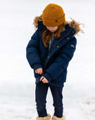 Cozy kid in a sleek blue City Transit Coat with faux fur hood, ready to conquer winter in style.