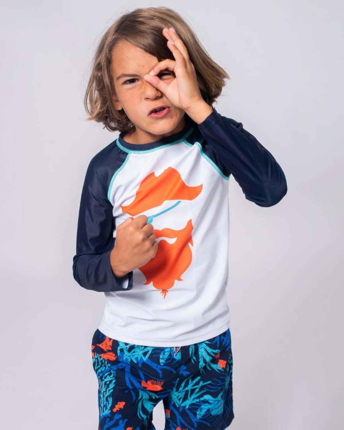 Boy in Blackbeard Rash Guard making a pirate face, ready for beach adventures.
