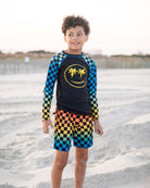 Charming kid in vibrant Happy Surfing Rash Guard with checkerboard pattern, ready for beach adventures and summer fun!
