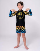 Stylish boy modeling the Happy Surfing Rash Guard, showcasing vibrant checkerboard design and UPF 50+ protection for endless fun!
