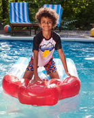 Cheerful kid in Storm Cloud Rash Guard splashing on a floatie at the pool, ready for summer fun in stylish kids clothes!