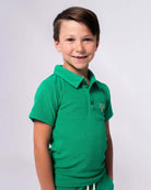 Stylish boy in a Kelly Green Fairbanks Polo, rocking a cool palm tree design—ideal for playdates and family fun!