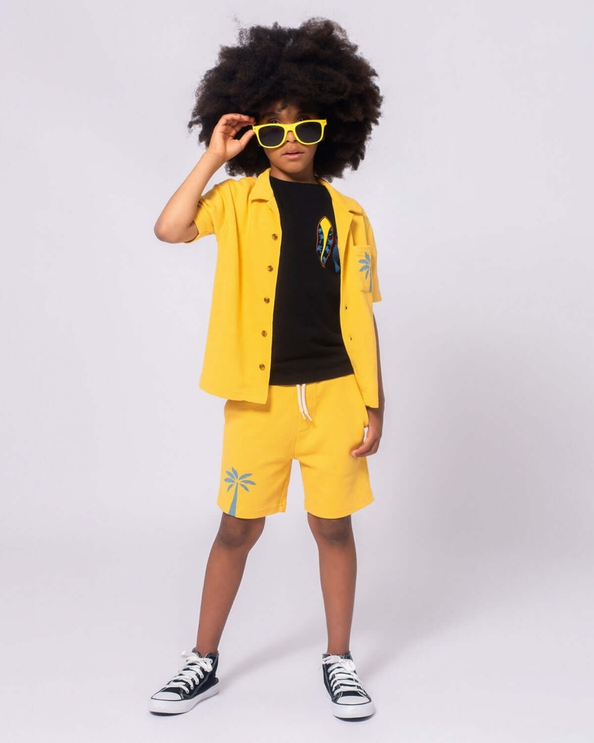 Child wearing Sunny Smile/Palm Tree Resort Shirt and matching yellow shorts, stylish island vibes outfit.
