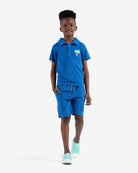 Stylish boy in blue polo and shorts, showcasing Appaman's Surf the Web Fairbanks Polo—a staple for trendy kids' clothes.