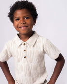 Stylish little boy rocking the Fairbanks Polo with playful surfboard design, perfect for bright days and beach vibes!