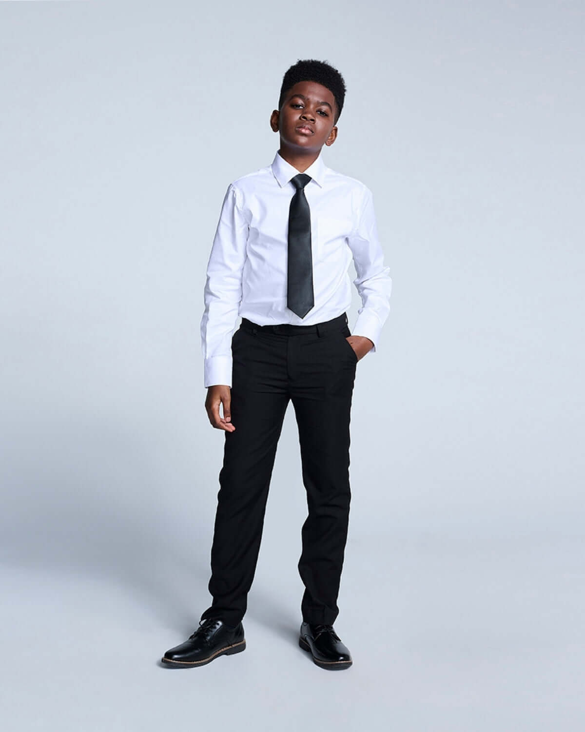 Boy wearing black suit pants with white shirt and tie, showcasing stylish formal wear for kids.
