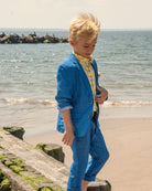 Stylish boy in a blue suit and bright shirt, enjoying a beach day—perfect kids clothes for summer fun!