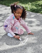 Cute child in pink tie-dye Samantha Sweatpants creating sidewalk art—stylish & fun kids clothes for back to school!