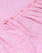 Close-up of playful pink fabric with golden polka dots, perfect for stylish kids' clothes.